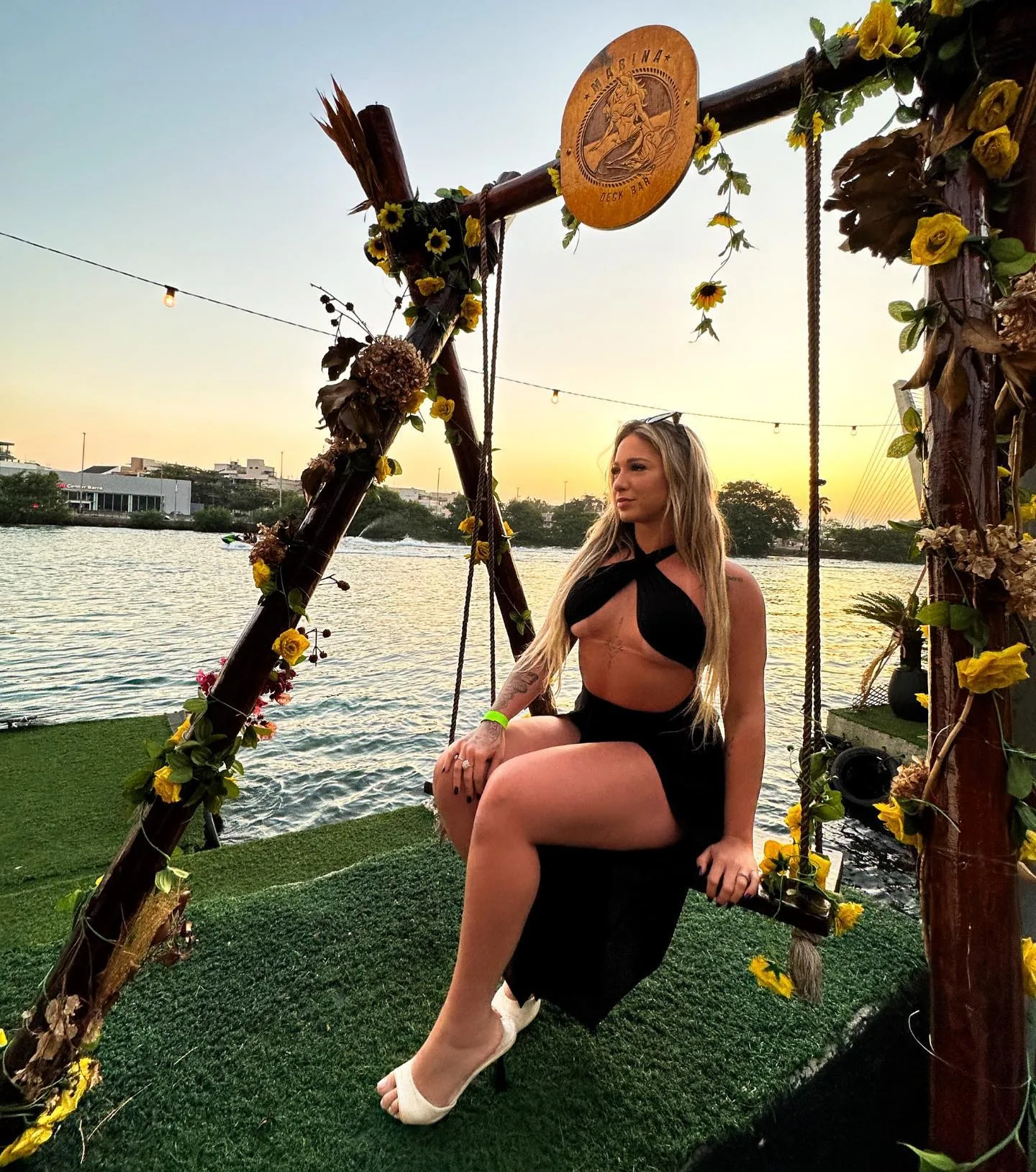 Convidada sentada no balanço decorado do Marina ao pôr do sol